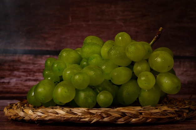 Foto un racimo de uvas verdes en una bandeja de hierba de esparto