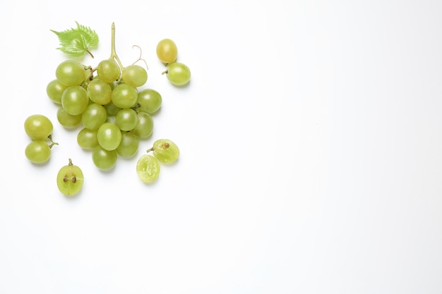 Foto racimo de uvas verdes maduras frescas con hojas en la vista superior de fondo blanco