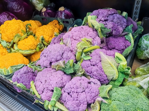 Racimos de cabezas de coliflor frescas de color amarillo, morado y verde en el mercado de agricultores.