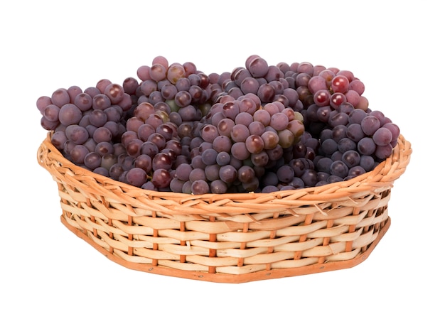 Racimos de uva roja en cesta de mimbre sobre fondo blanco.