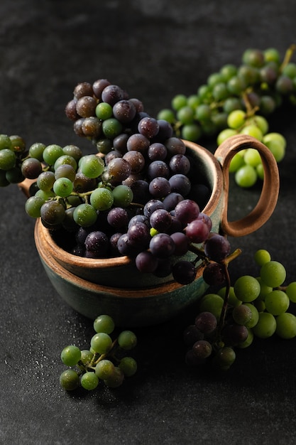 Racimos de uva en tazas de cerámica sobre fondo gris