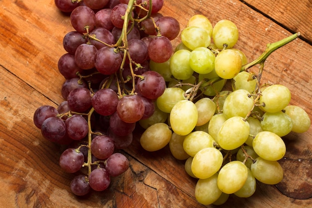 Racimos de uvas rojas y verdes en una mesa de madera