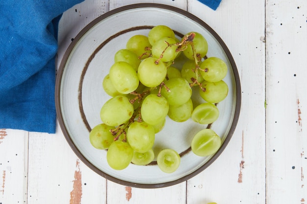 Racimos de uvas verdes maduras frescas en una mesa de madera