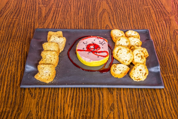 Ración de foie con mermelada y tostadas sobre mesa de madera