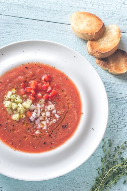 Foto una ración de gazpacho y pan en la mesa de madera.