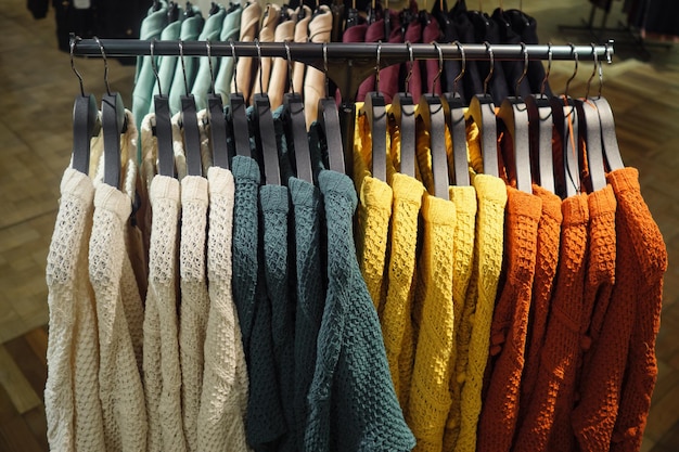 Rack com cabides de várias camisolas coloridas à venda na loja de roupas modernas