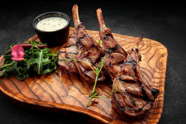 Rack de cordero con salsa y hierbas sobre una tabla de madera