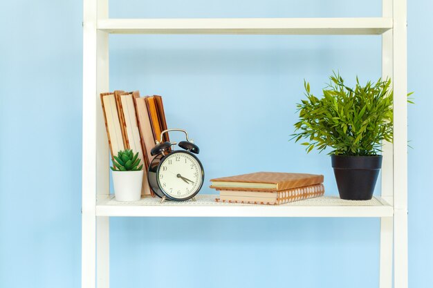 Rack de metal branco com livros em fundo azul