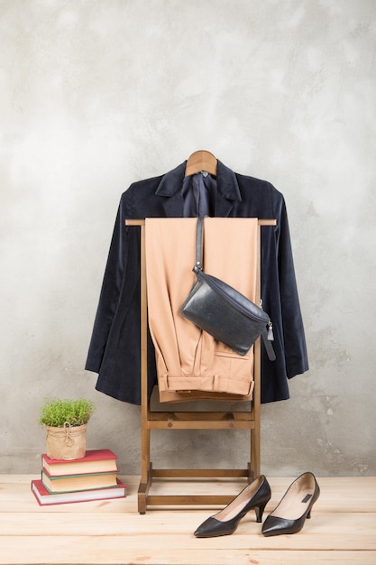 Rack de roupas de conceito de compras e estilo com casaco azul moderno e bolsa de calças e sapatos no chão