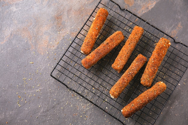 Rack mit leckeren Mozzarella-Sticks auf grauem Tisch