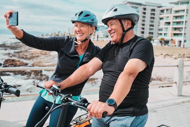 Radfahren, Lächeln und Fitness mit altem Ehepaar und Selfie für Social-Media-Training und Gesundheitstraining Wellness-Internet und Blog mit älteren Männern und Frauen auf dem Fahrrad für Sportübungen und Reisen
