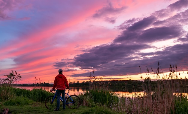 Radfahrer an der Küste des Flusses bei Sonnenuntergang im Sommer