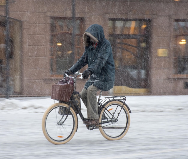 Radfahrer auf der Stadtfahrbahn an einem verschneiten Tag in Bewegungsunschärfe. Unscharfes Bild