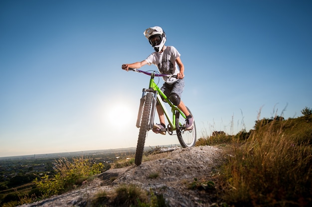 Radfahrer, der abwärts auf Mountainbike auf dem Hügel fährt