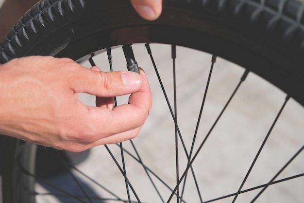 radfahrer, der die kappe auf den nippel schraubt, während er das rad seines fahrrads in der nähe repariert