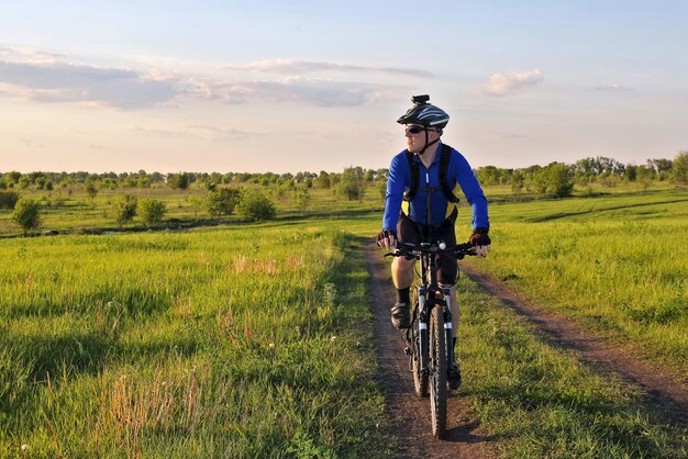 Radfahrer fährt an einem sonnigen Tag auf der Straße auf einem Feld