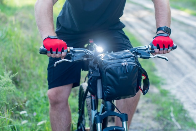 Radfahrer in Handschuhen auf einem Mountainbike mit einer Tasche am Lenker.