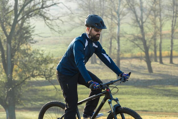 Radfahrer in Hose und Fleecejacke auf einem modernen Carbon-Hardtail-Bike mit Luftfedergabel Der Typ oben auf dem Hügel fährt Fahrrad