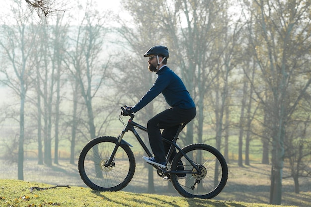 Radfahrer in Hose und Fleecejacke auf einem modernen Carbon-Hardtail-Bike mit Luftfedergabel Der Typ oben auf dem Hügel fährt Fahrrad