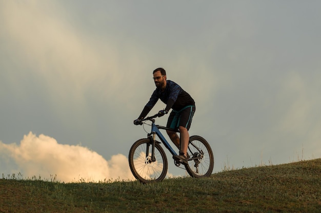 Radfahrer in Hose und Fleecejacke auf einem modernen Carbon-Hardtail-Bike mit Luftfedergabel Der Typ oben auf dem Hügel fährt Fahrrad