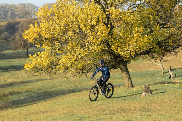 Radfahrer in Hose und Fleecejacke auf einem modernen Carbon-Hardtail-Bike mit Luftfedergabel Der Typ oben auf dem Hügel fährt Fahrrad