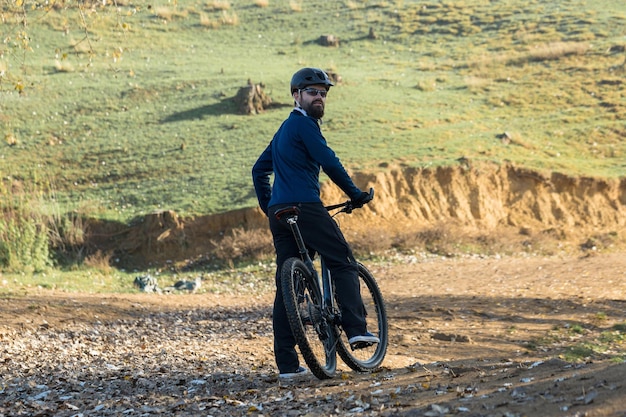 Radfahrer in Hose und Fleecejacke auf einem modernen Carbon-Hardtail-Bike mit Luftfedergabel Der Typ oben auf dem Hügel fährt Fahrrad