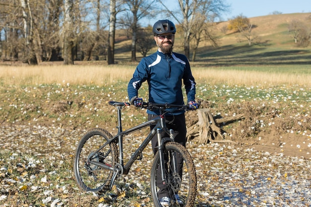 Radfahrer in Hose und Fleecejacke auf einem modernen Carbon-Hardtail-Bike mit Luftfedergabel fährt im Gelände