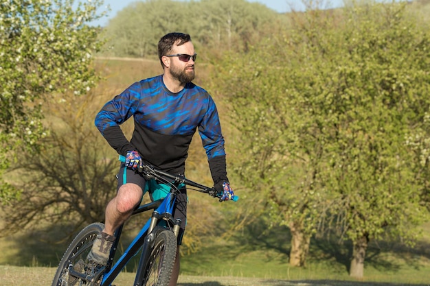 Radfahrer in Hose und Fleecejacke auf einem modernen Hardtail-Bike mit Federgabel fährt Offroad