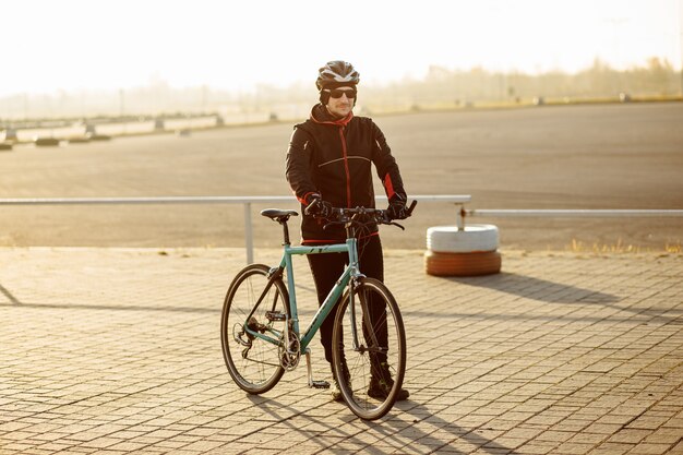 Radfahrer in schwarzer Kleidung und Helmzüge auf einem Fahrrad