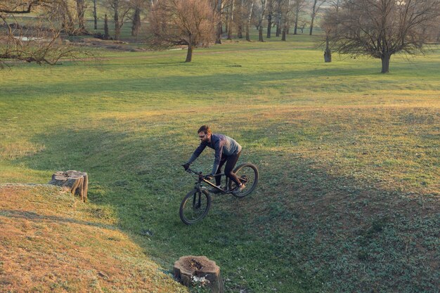 Radfahrer in Shorts und Trikot auf einem Carbonrad mit Luftfedergabel auf einer Klippe stehend