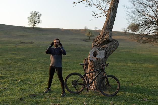 Radfahrer in Shorts und Trikot auf einem modernen Carbon-Hardtail-Bike mit einer Luftfedergabel, die auf einer Klippe vor dem Hintergrund eines frischen grünen Frühlingswaldes steht