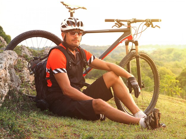 Radfahrer mit seiner Mountainbike, die den schönen Sonnenaufgang betrachtet. Radfahrer auf einem Hügel.