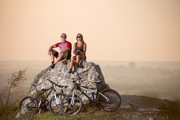 Radfahrer sitzen auf einem großen Stein, daneben sind Sportfahrräder