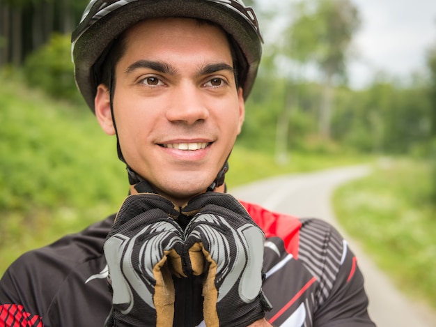 Radfahrermann, der seinen Sportsturzhelm und Lächeln trägt.