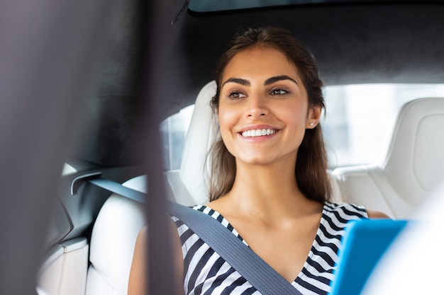 Radiante empresaria. Transmisión de la empresaria sosteniendo la tableta sonriendo mientras está sentado en el coche