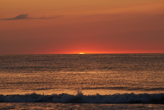 Radiante puesta de sol sobre el océano El sol resplandeciente se hunde en el horizonte