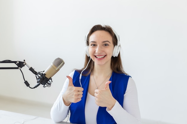 Radio, Blogging, Broadcast-Konzept - Junge Frau, die im Radio arbeitet und Daumen nach oben isoliert auf weißem Hintergrund zeigt.