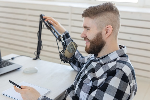 Radio-, DJ-, Blogger- und People-Konzept - junger Mann, der im Radiostudio arbeitet und am Mikrofon spricht
