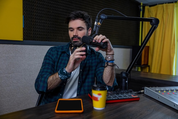 Radio-DJ. Dunkelhaariger junger Mann mit Mikrofon in der Hand