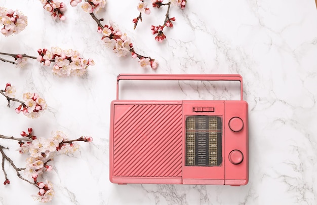 Rádio fm retrô com belos galhos de flores brancas em fundo de mármore Conceito de música de primavera Vista superior plana