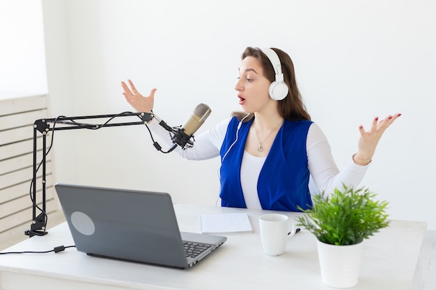 Radio-Host-Konzept - Frau arbeitet als Radio-Host, der vor dem Mikrofon über Weiß sitzt