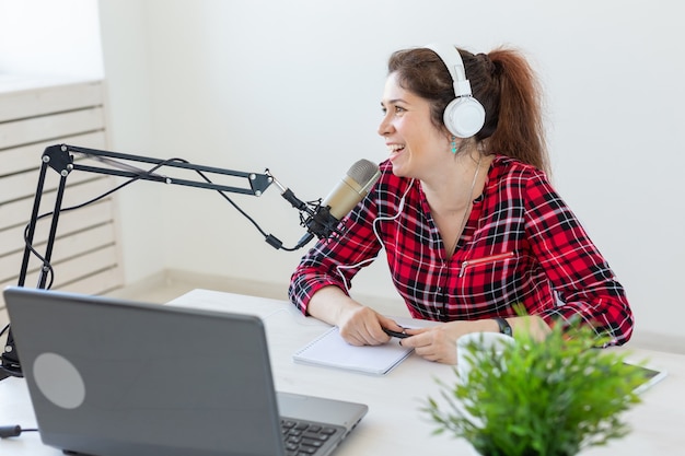 Radio-Host-Konzept - Freudige Frau im karierten Hemd, die am Radio arbeitet