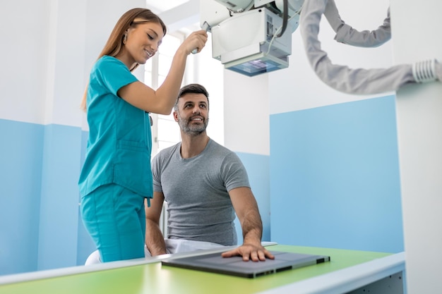Radiologe bereitet Patientin auf Röntgenaufnahme der Hand in der Nähe des Röntgengeräts vor Radiologe nimmt Röntgenaufnahme des Patienten, der auf einer Trage liegt