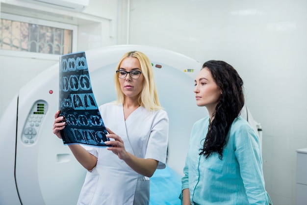 Radiologe mit einer Patientin, die einen CT-Scan untersucht