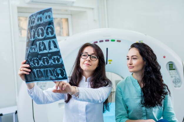 Radiologe mit einer patientin, die einen ct-scan untersucht.