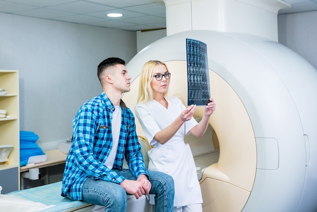 Foto radiologista com um paciente do sexo masculino examinando uma ressonância magnética.