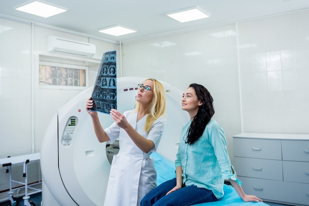 Radiologista com uma paciente examinando uma tomografia computadorizada
