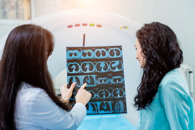 Radiologista com uma paciente examinando uma tomografia computadorizada.