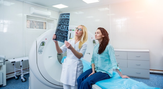 Radiologista com uma paciente examinando uma tomografia computadorizada.