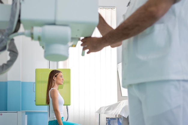 Foto radiologista configurando a máquina para fazer raio-x de paciente do sexo feminino radiologista e paciente em uma sala de raio-x sistema clássico de raio-x montado no teto equipamento médico